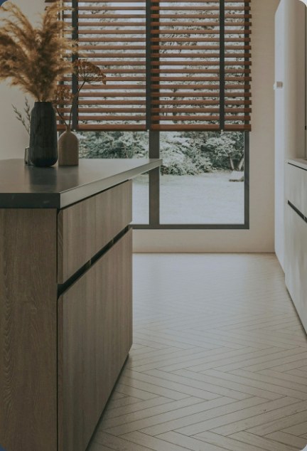 A wood kitchen island beside a window with slatted blinds
